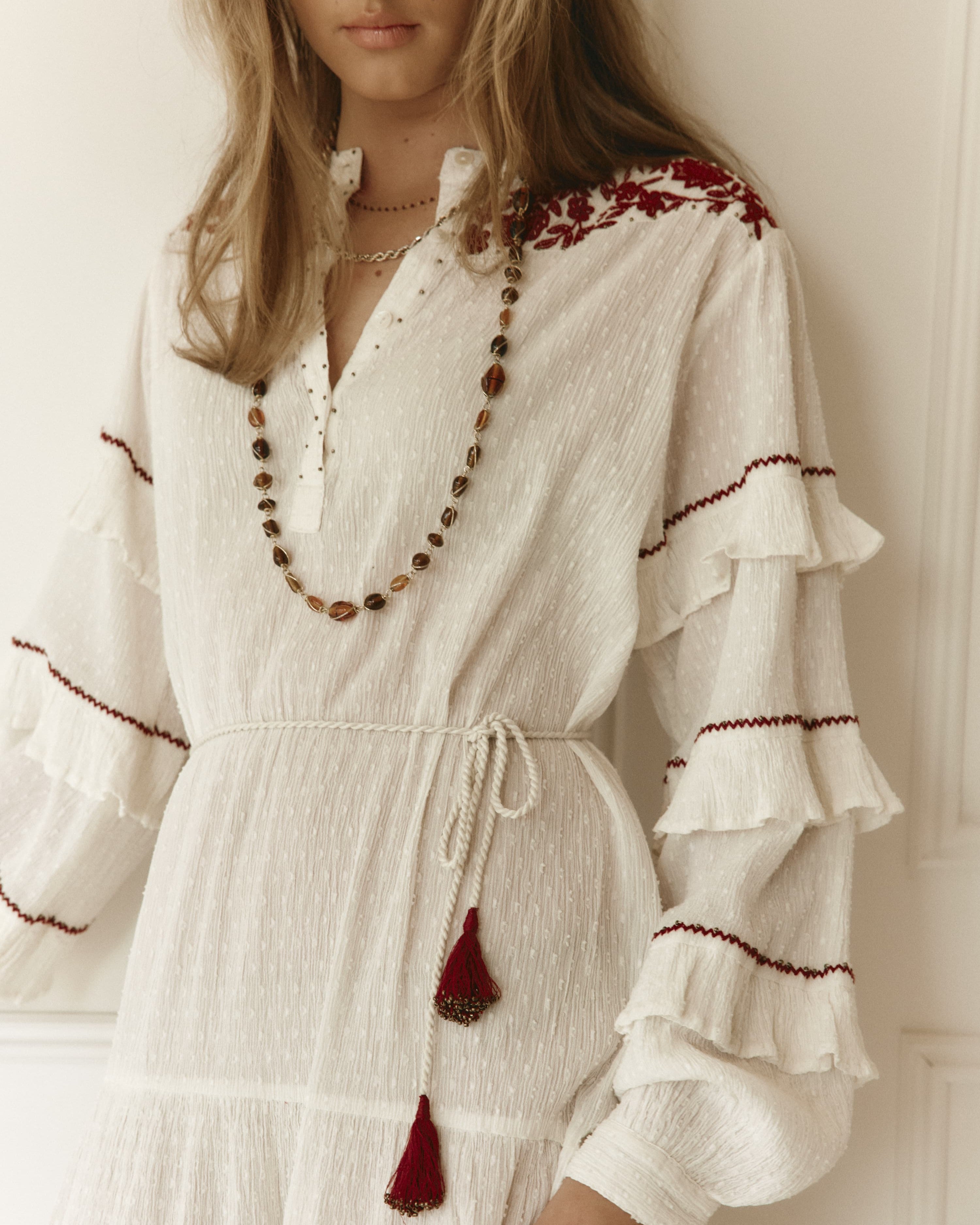 Lakoen Anais Dress in white cotton dobby with floral embroidery in burgundy and frilled bishop sleeves