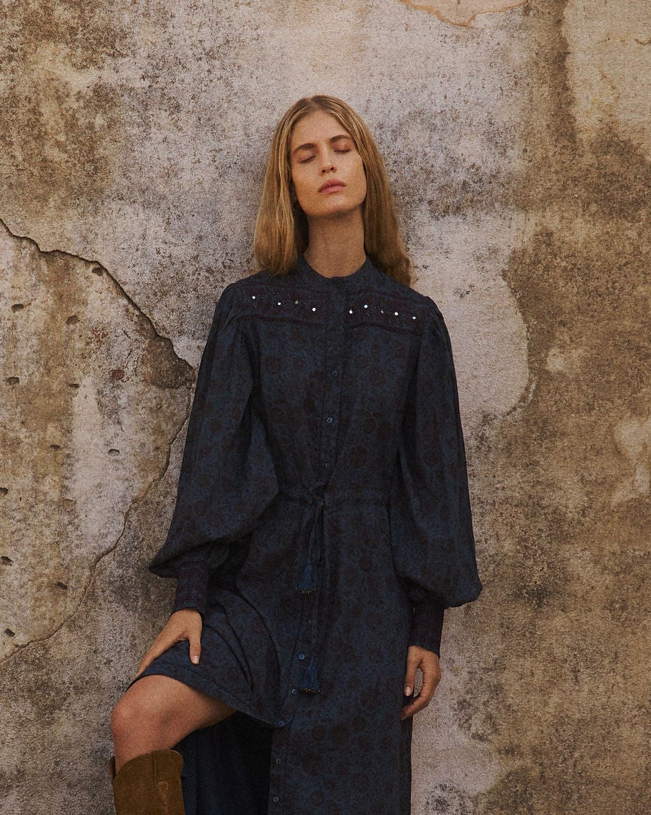 woman wears indigo Lakoen Delphine shirtdress made from soft cotton, smocked with shisha mirror work and a subtle burgundy floral print